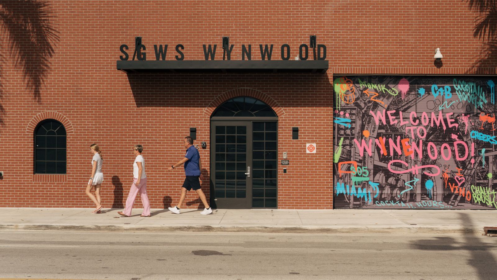 Calle de Wynwood en Miami cerca de DUOS Wynwood en 335 NW 28th Street, con un mural que dice Welcome to Wynwood sobre una pared de almacén