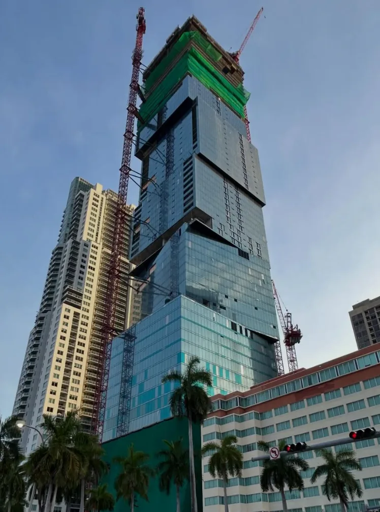 Waldorf Astoria Residences Miami at dusk, tower cranes over the stacked cube design, 300 Biscayne Blvd