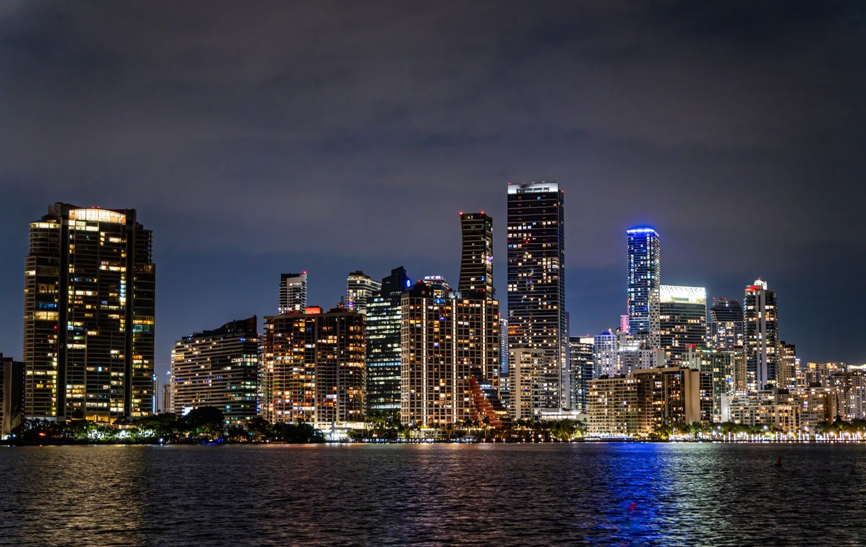 Horizonte iluminado de Miami à beira-mar à noite onde condos de luxo de marca atraem compradores globais
