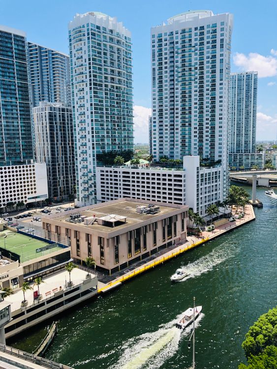 Torres de condomínios à beira da água em Brickell, junto ao rio Miami, onde as reduções de seguro de 2026 aliviam as apólices mestras das HOAs