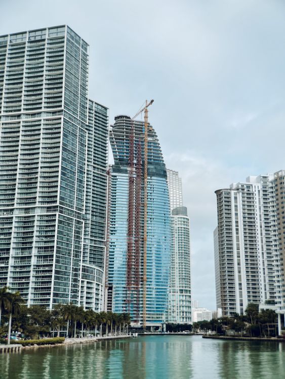 Uma torre de condomínios de Miami em construção com um guindaste à beira da água, a fase de pré-construção que The Standard Residences já superou com seu empréstimo quitado