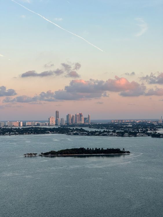 Vista aérea das ilhas da baía e do horizonte de Miami ao entardecer, o mercado troféu à beira-mar que aperta quando os bilionários da Califórnia que se realocam compram