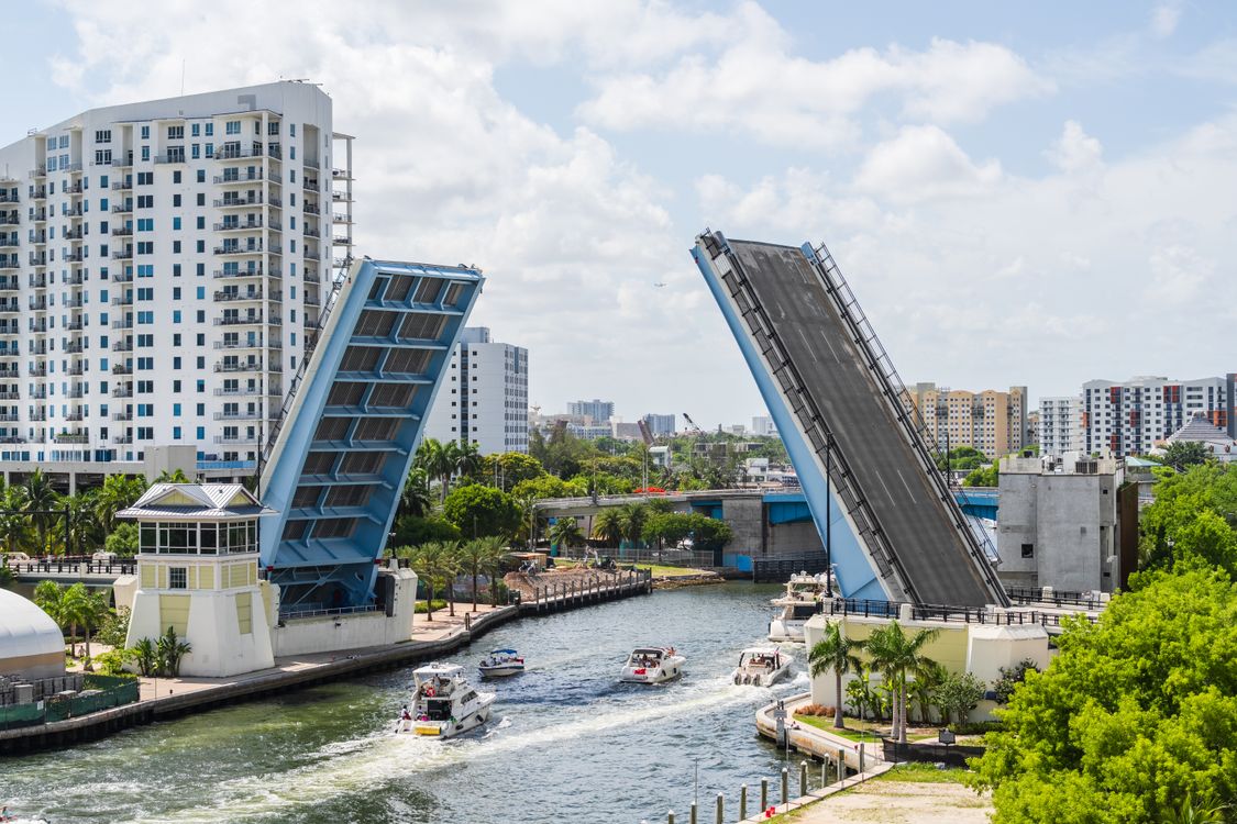 Un puente levadizo del sur de Florida elevado sobre un canal con barcos pasando y edificios detrás