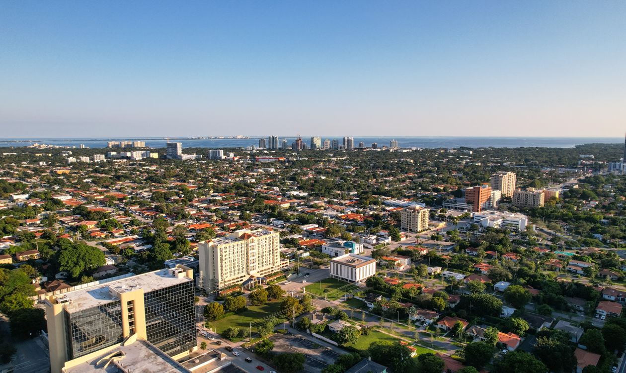 Vista aérea sobre vecindarios de Miami mirando hacia las torres y el agua abierta de la bahía de Biscayne