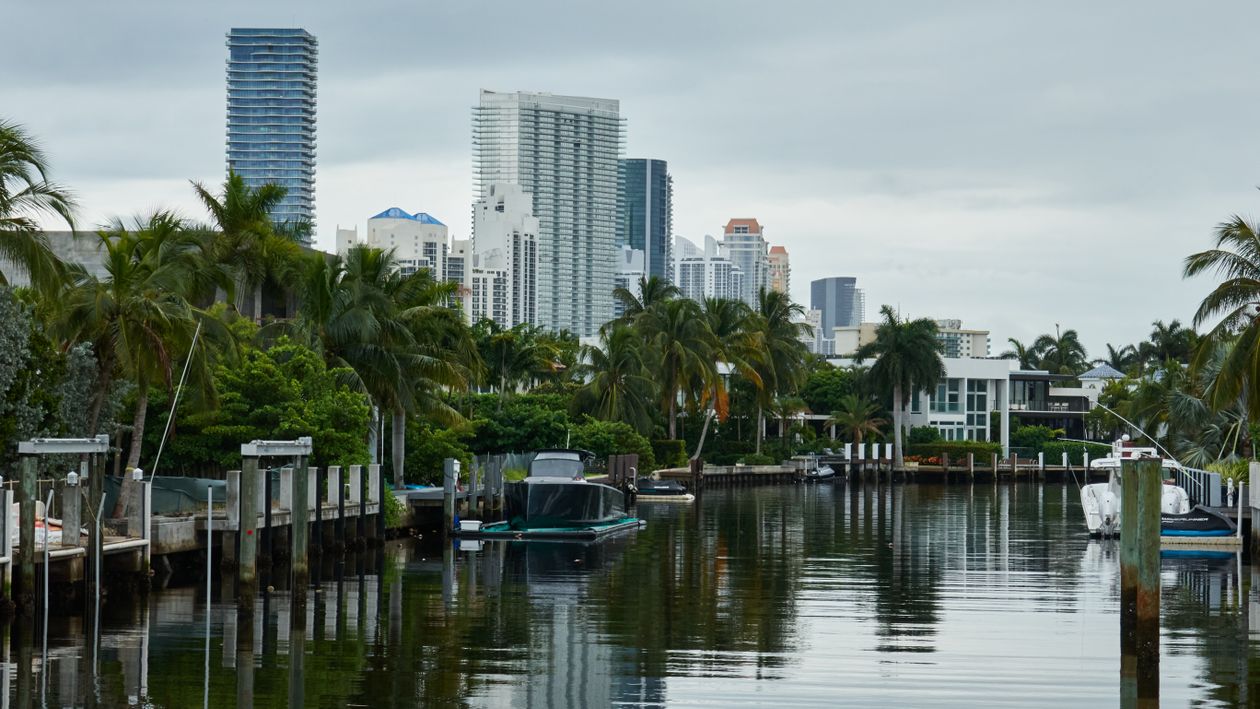 Embarcaciones atracadas en un canal de Miami con torres de condominios detrás de las palmeras