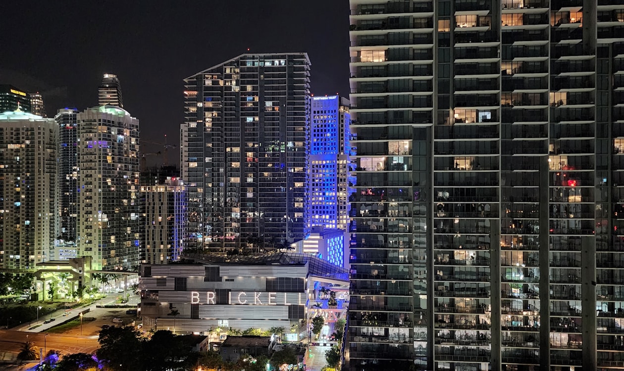 Torres de condomínios de Brickell iluminadas à noite em Miami, onde os compradores combinam unidades em dúplex sob medida nas alturas