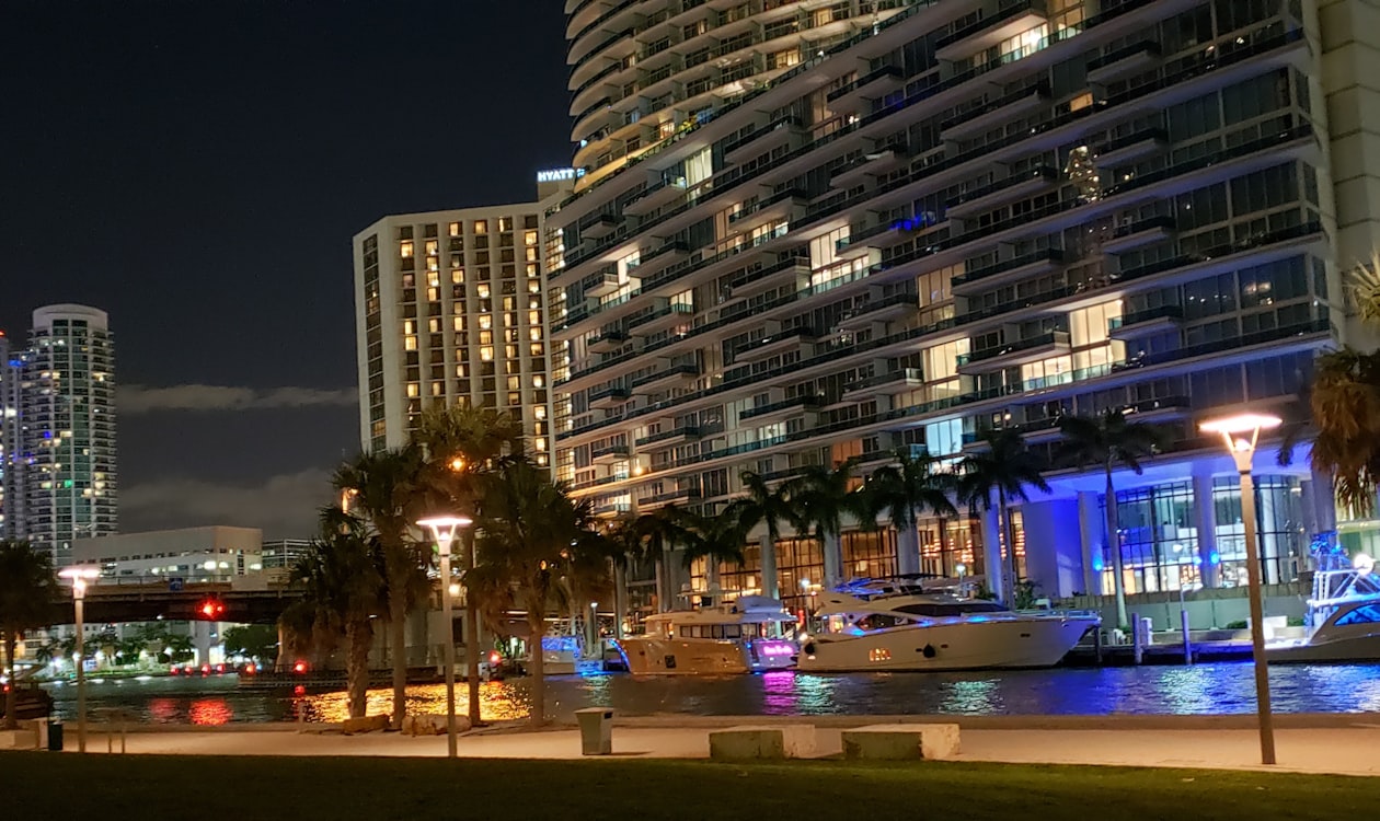 Torre de condomínios à beira-mar em Miami iluminada à noite com iates na água