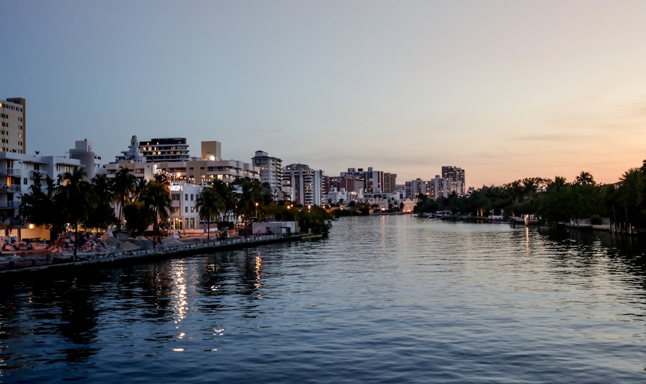 Condomínios à beira-mar de Miami Beach e orla com palmeiras ao entardecer ao longo de um canal tranquilo da baía