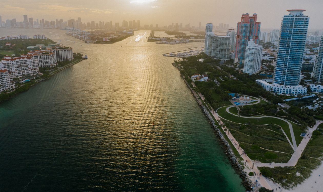 Vista aérea sobre o Government Cut ao pôr do sol com Fisher Island à esquerda e o skyline de Miami ao fundo
