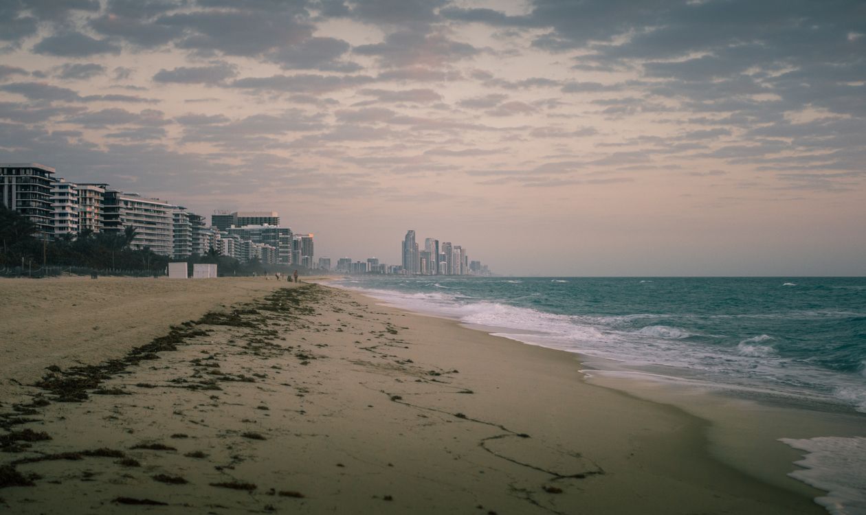 Orla de Miami Beach ao entardecer com torres de apartamentos à beira-mar ao longo da costa