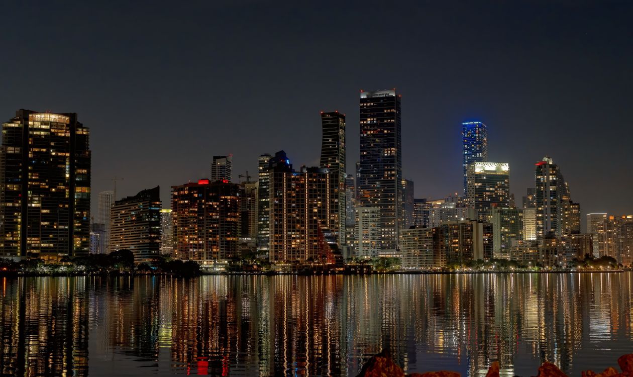 Torres de condomínios e escritórios de Brickell iluminadas à noite refletidas na Biscayne Bay em Miami