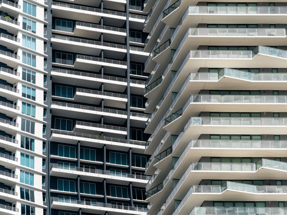 Vista en diagonal de balcones apilados en torres residenciales contiguas de Miami con palmeras plantadas en una terraza