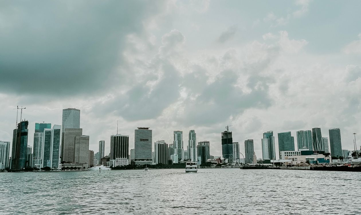 El horizonte del centro de Miami visto desde la bahía de Biscayne bajo nubes densas, con grúas de construcción visibles entre las torres de condominios