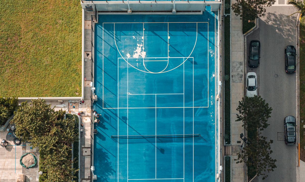 Aerial view of an elevated tennis and basketball amenity deck at a Miami condo building, the type of parcel at issue in the Aventura suit