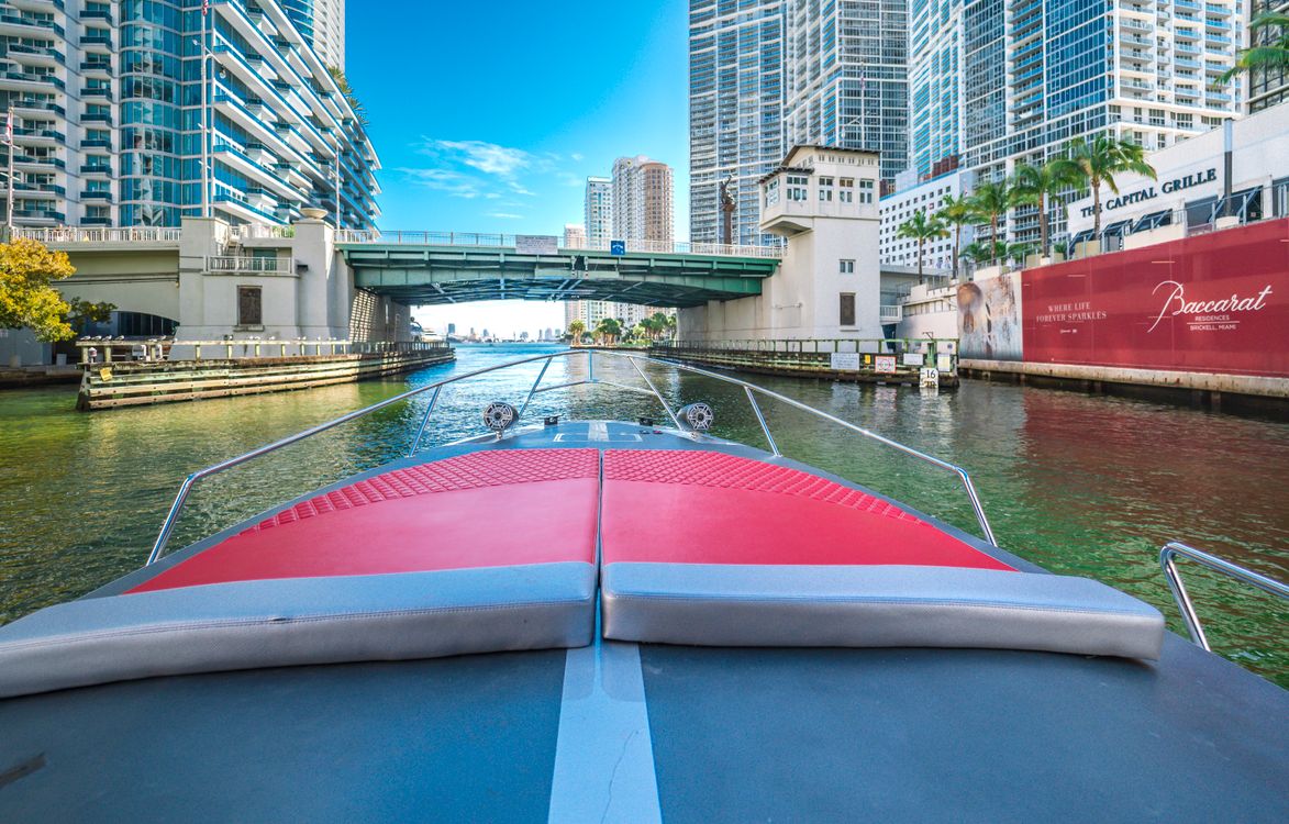 Bote en el Río Miami pasando bajo el puente de Brickell Avenue entre torres de condominios en Miami Florida