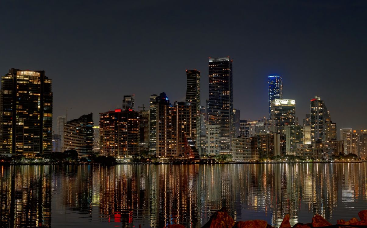 Horizonte de Brickell con torres de condominios iluminadas reflejadas en el agua de noche en Miami Florida