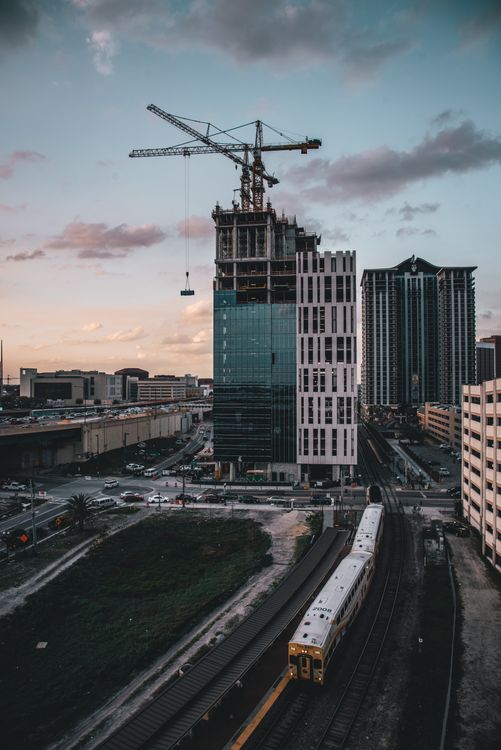 Uma torre de condomínios do sul da Flórida em construção ao entardecer, com um guindaste sobre os andares superiores inacabados