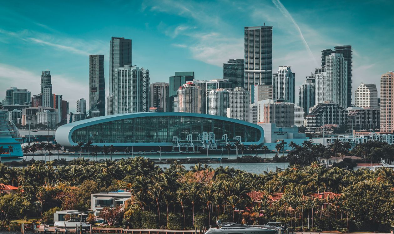 Las torres del centro de Miami y la terminal de PortMiami vistas al otro lado de Biscayne Bay desde una costa bordeada de palmeras