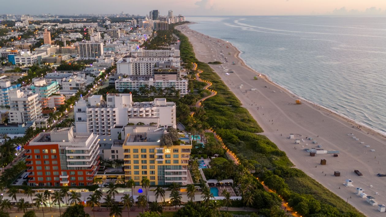 Aerial view of Miami Beach oceanfront towers, palm-lined beach path and the Atlantic coastline at dusk