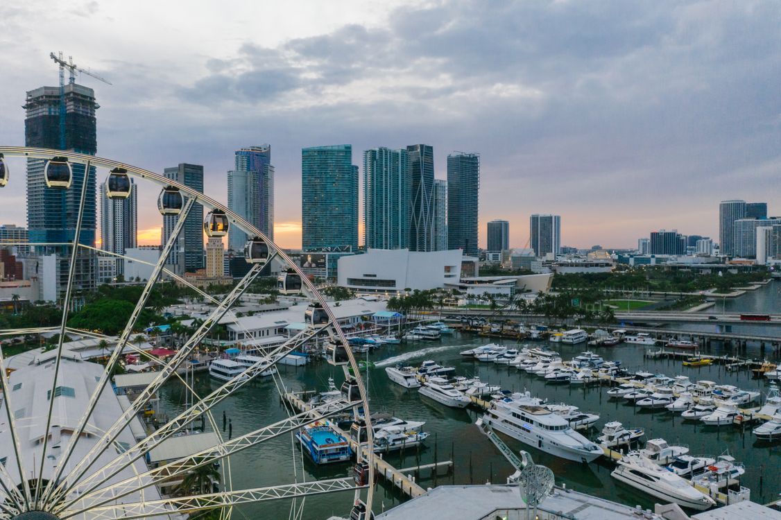 Downtown Miami condo towers and construction crane above a full Bayside marina at dusk