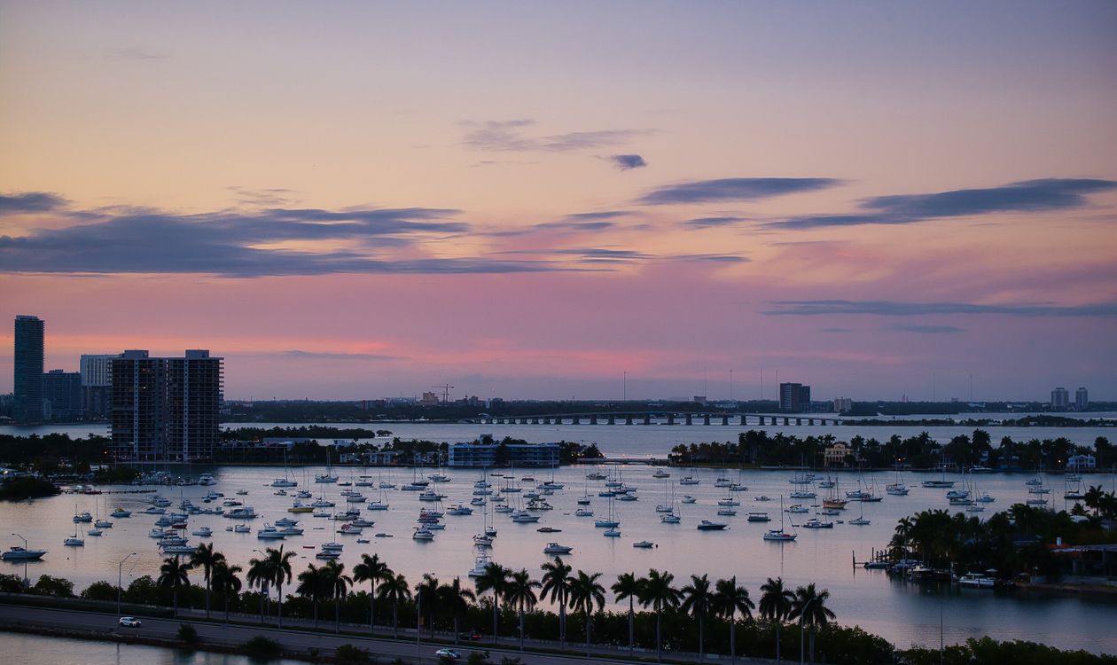 La bahía de Biscayne al atardecer con botes fondeados, una calzada y torres frente al mar en Miami