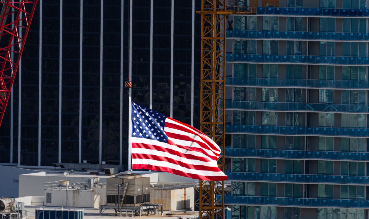 Tower cranes beside a Miami condominium tower under construction with its glass curtain wall going in