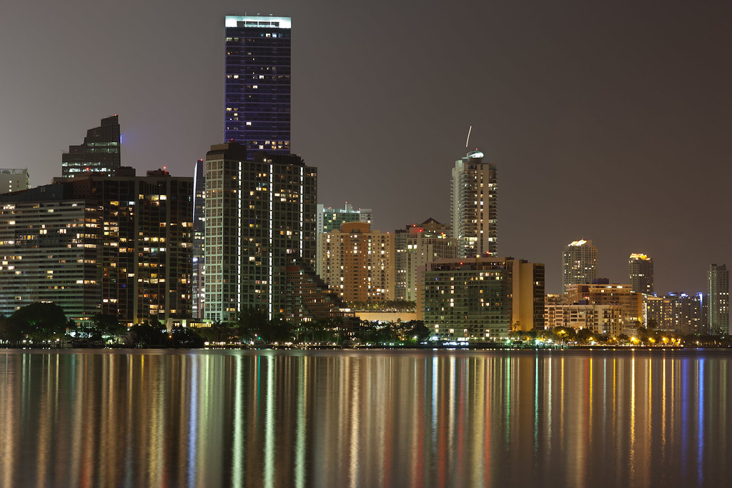 Brickell condo towers lit at night reflected on Biscayne Bay in Miami