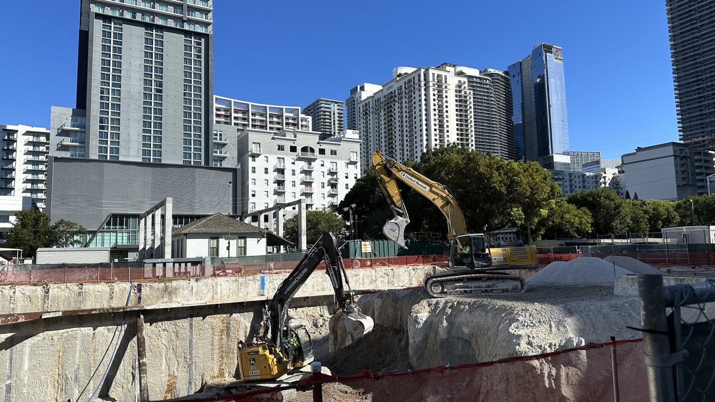 Excavación y trabajos de cimentación en la obra de 1 Southside Park en Brickell, con torres residenciales de Miami al fondo