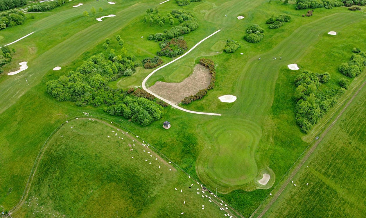 Vista aerea de una torre Mediterranean Revival de lujo con fairways de golf y palmeras tropicales, representativa de Trump National Doral y las comunidades cerradas con campos de golf de Doral