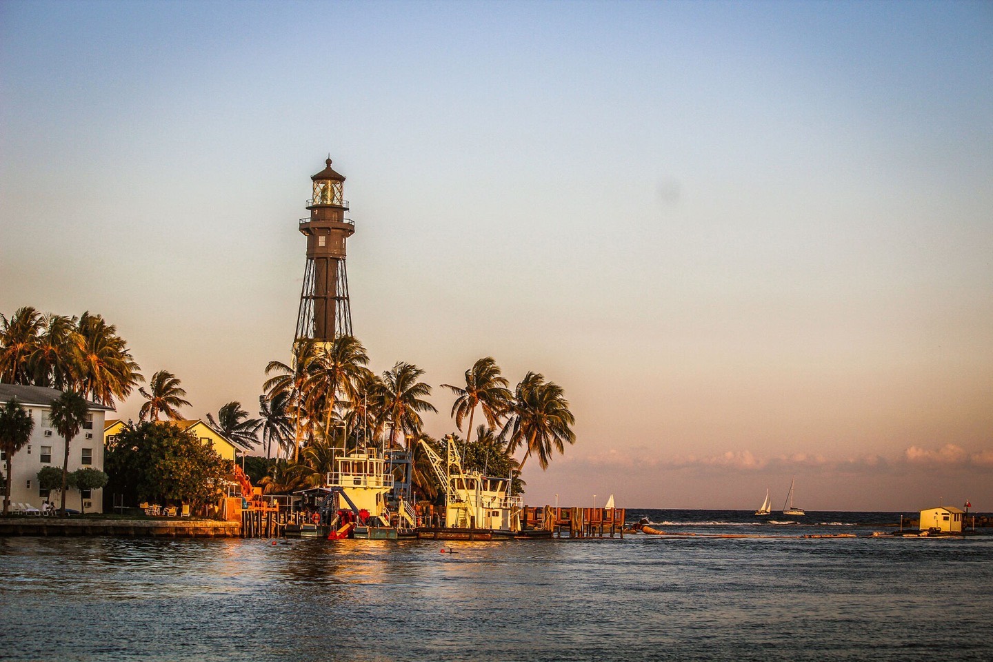 Faro de Hillsboro Inlet al atardecer con botes en el canal de la desembocadura en Hillsboro Beach, Florida