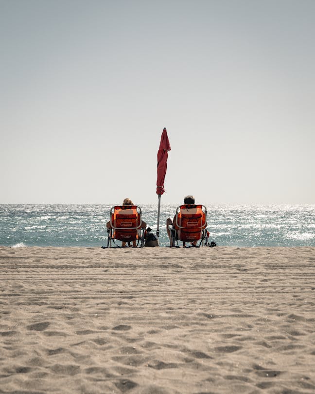 Bañistas relajándose bajo una sombrilla sobre la arena en Hollywood Beach, Florida, frente al océano Atlántico