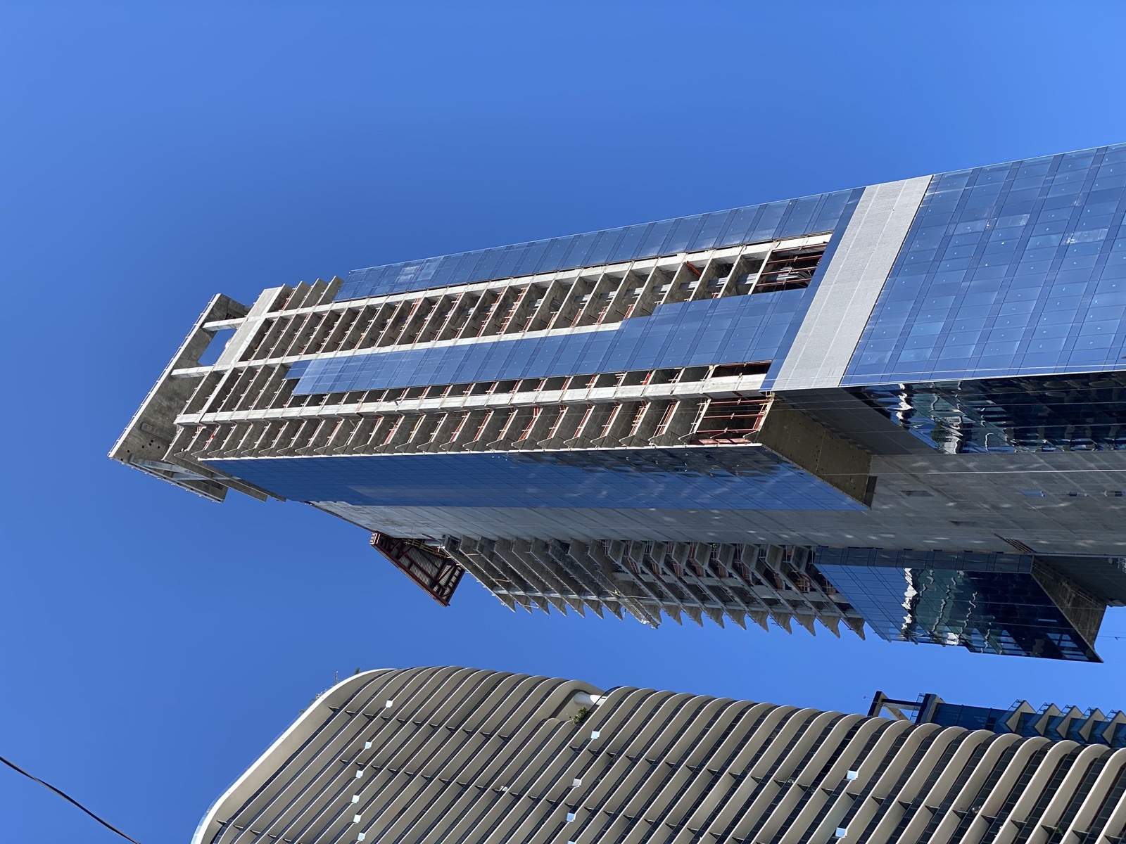 Torre de condominios de Miami subiendo en altura con el muro cortina de vidrio ascendiendo por la estructura de hormigón