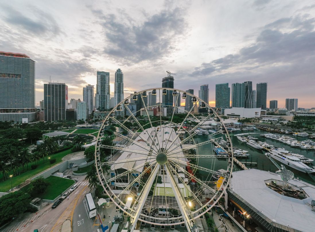 Downtown Miami à beira da baía ao entardecer com a roda-gigante, a marina e as torres de condomínios da Biscayne Boulevard