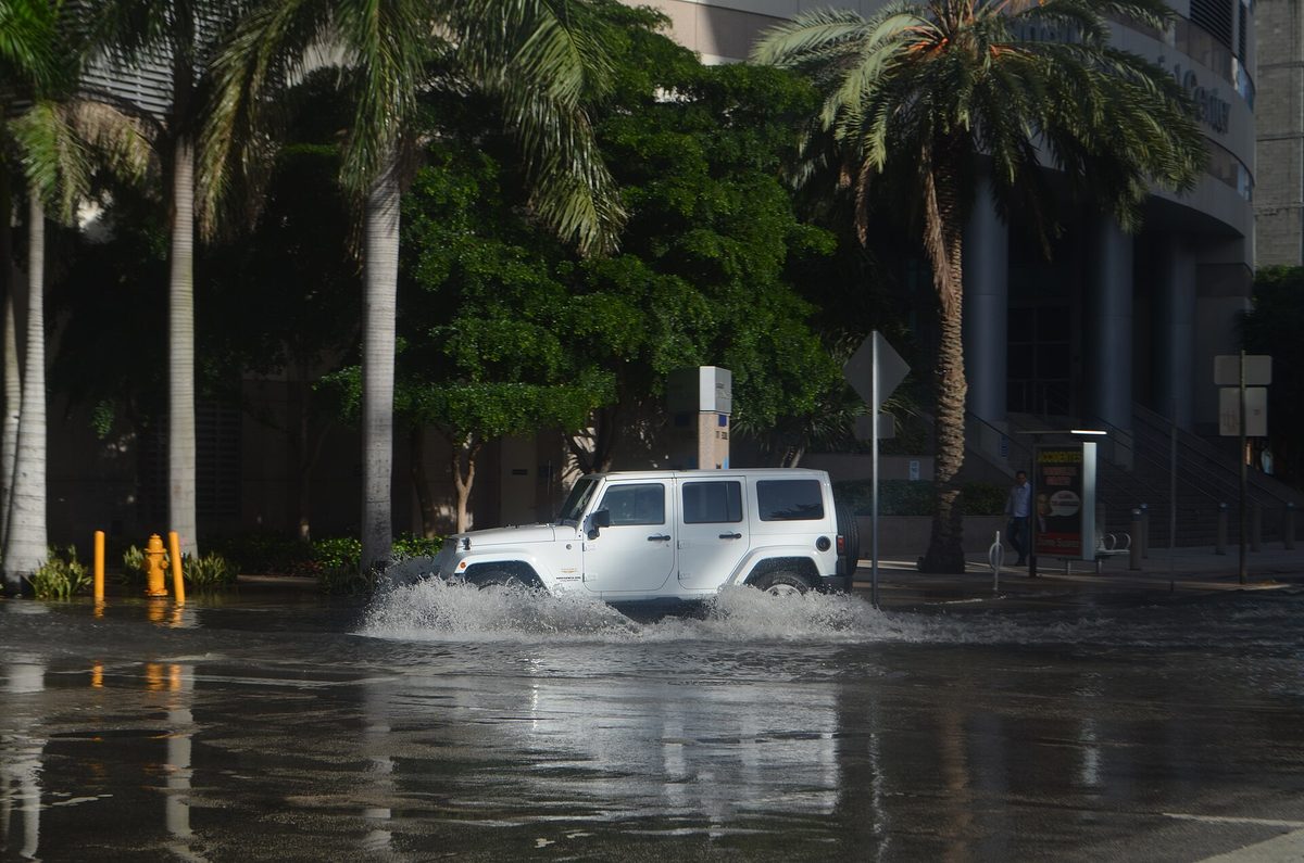 Veículo atravessando água parada de maré em uma rua de Downtown Miami