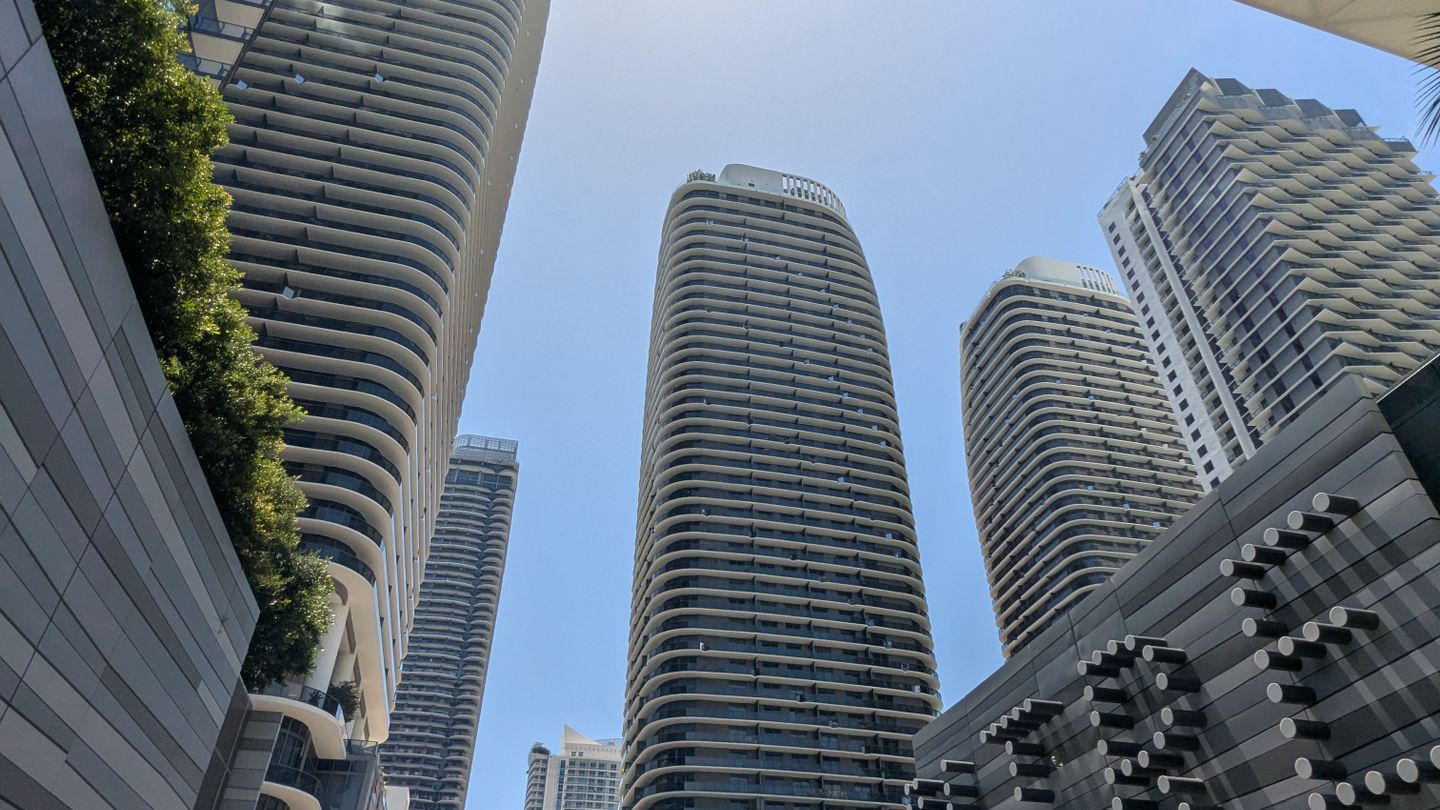 Brickell condo towers with curved balconies seen from street level beneath the Brickell City Centre canopy