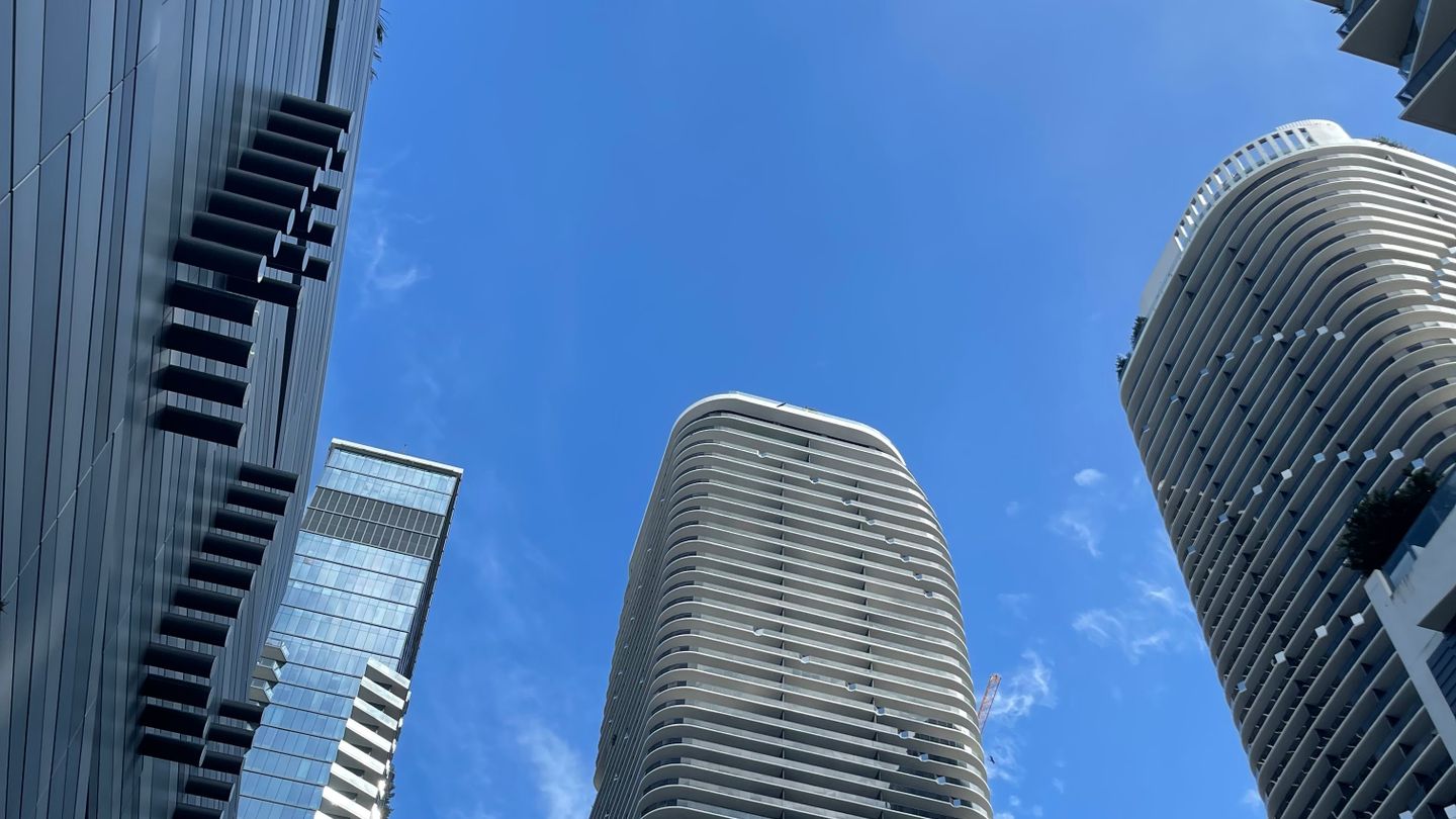 Brickell luxury condo towers against a blue sky with a construction crane visible between them