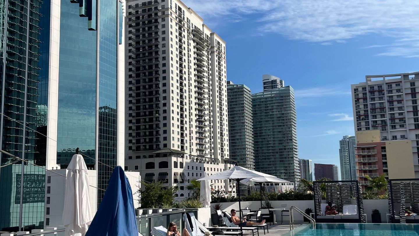 A Brickell rooftop pool deck with loungers and cabanas, Miami condo towers rising behind it
