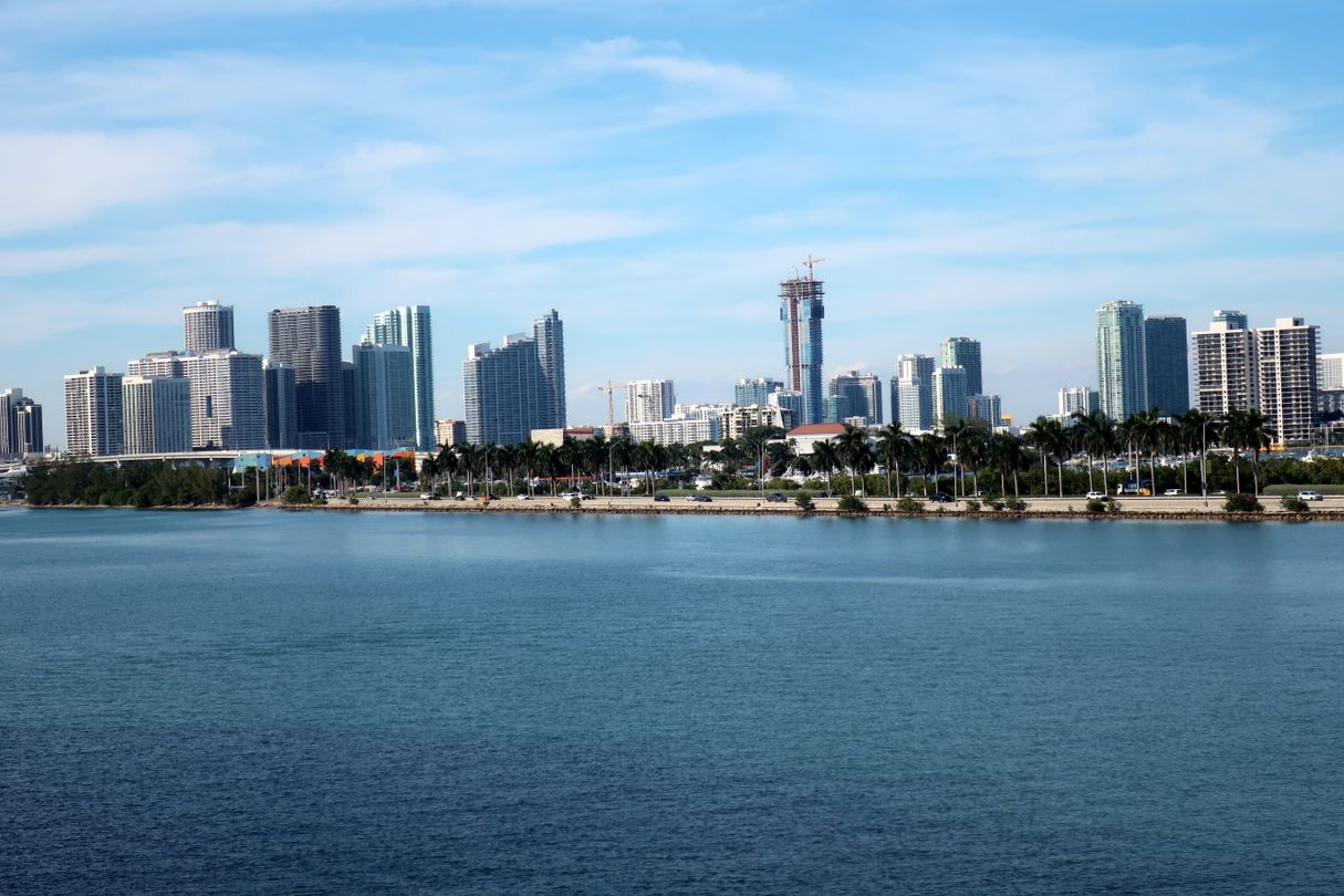 The Edgewater and Downtown Miami skyline seen across Biscayne Bay with one tower still under construction and a crane on its crown