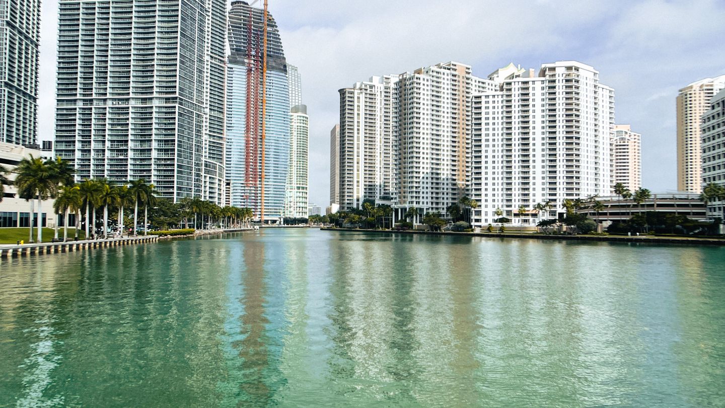 Torres de condomínios de luxo de Brickell refletidas na água, onde os compradores estrangeiros absorvem quase metade das obras novas