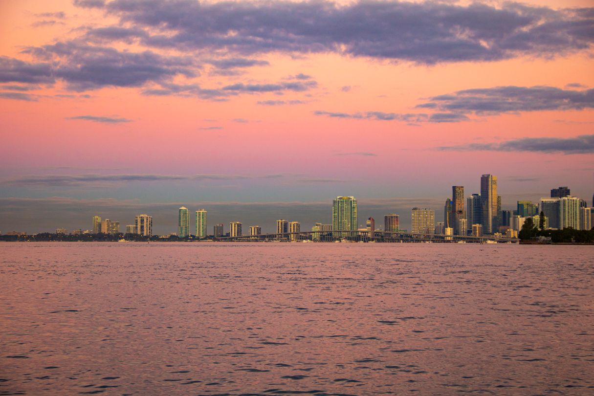 Skyline de Miami al atardecer con cielo rosado sobre la bahía de Biscayne y torres de condominios distantes