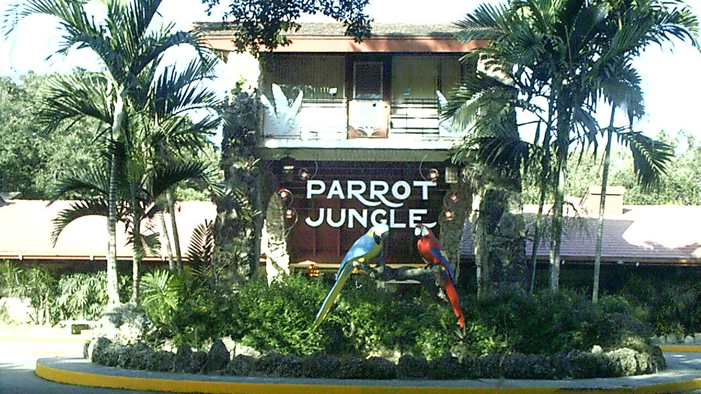 La misma entrada de Pinecrest fotografiada en 2002 con su letrero original de Parrot Jungle y dos guacamayos en una percha