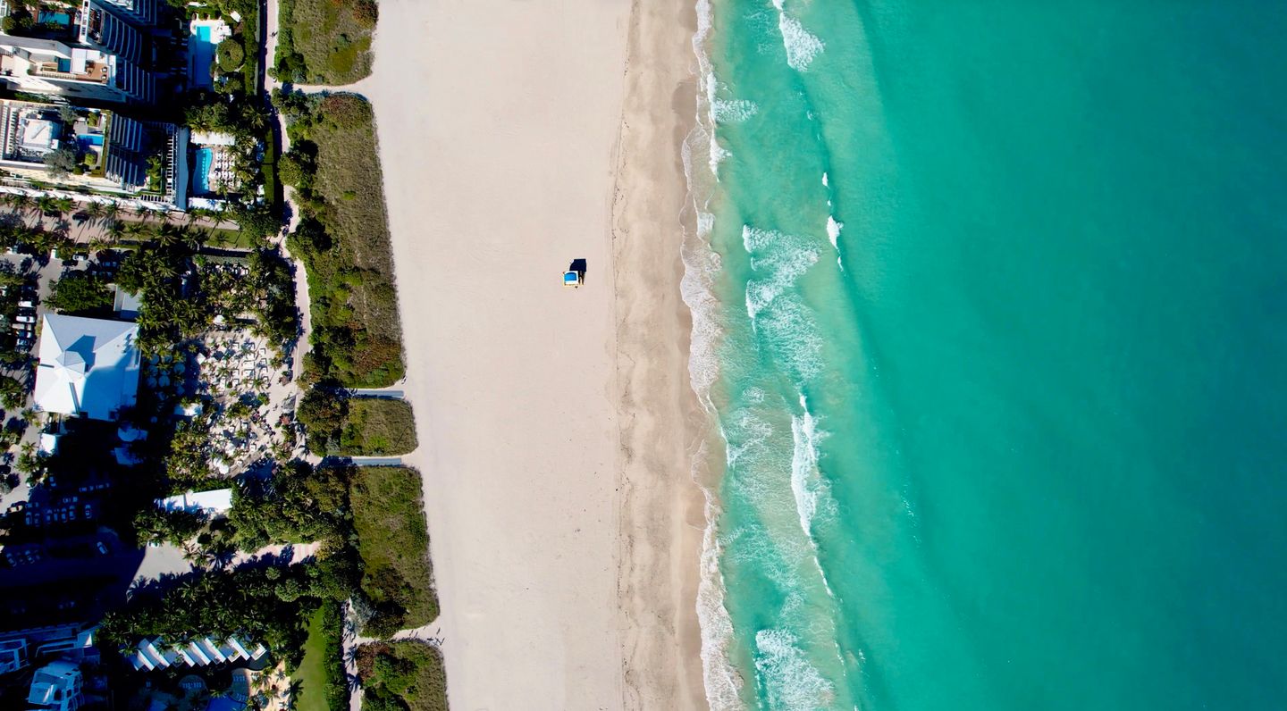 Overhead view of a Miami Beach oceanfront block where hotel-service buildings sit directly beside conventional condominium stock