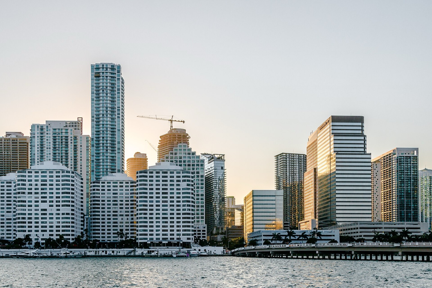 Brickell waterfront condominium towers in Miami at golden hour with a tower crane on a building under construction