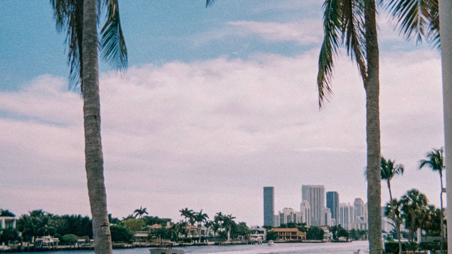 Waterfront single-family homes on a Biscayne Bay island with the Downtown Miami skyline behind them