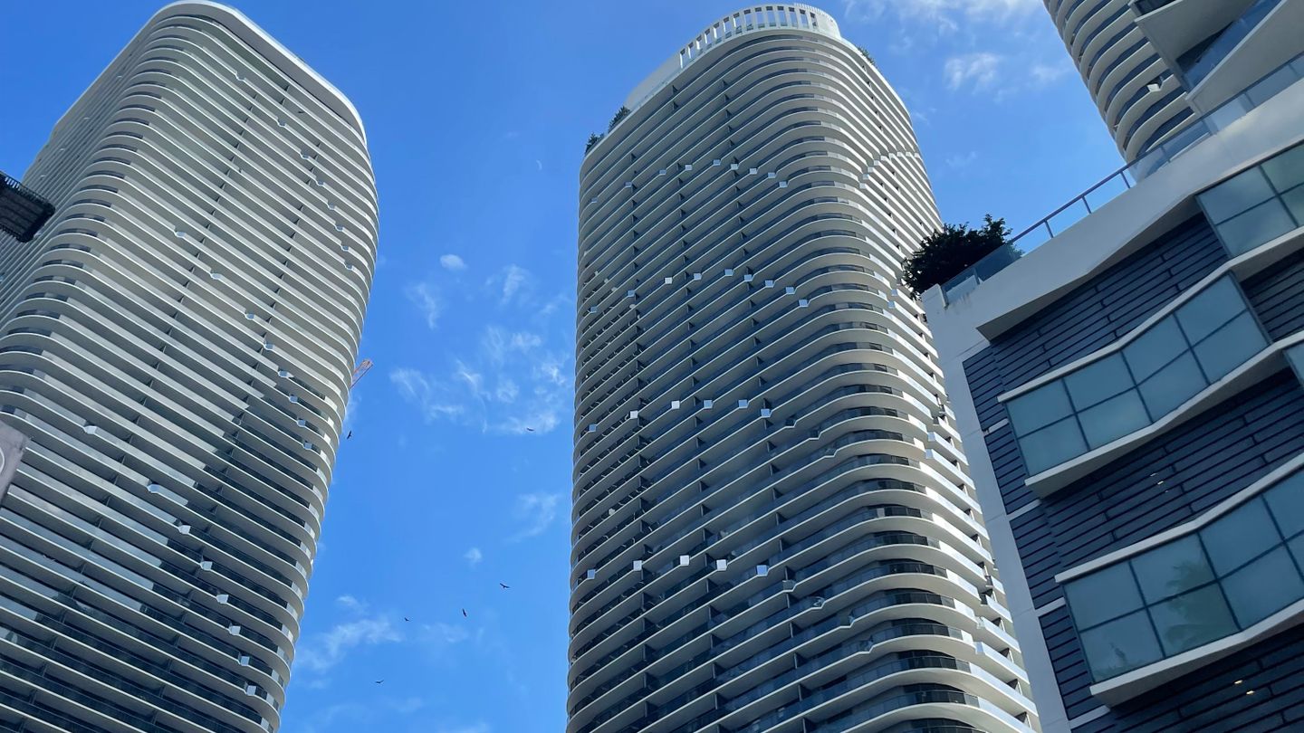Two residential condominium towers in Downtown Miami seen from street level against a clear sky