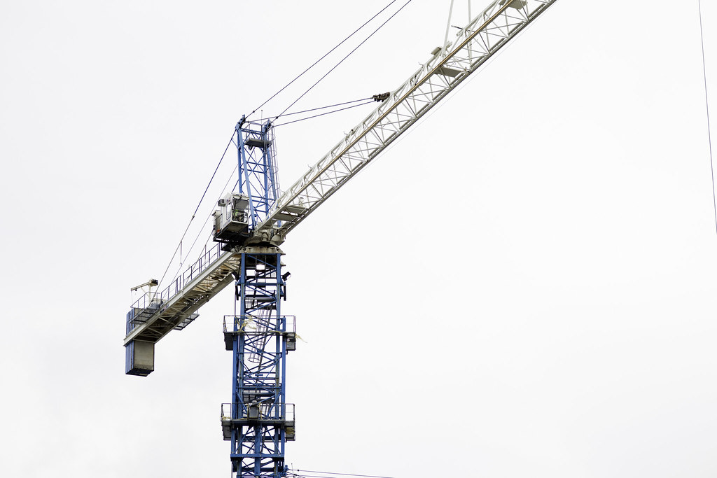 A blue tower crane rising over a Brickell construction site in Miami