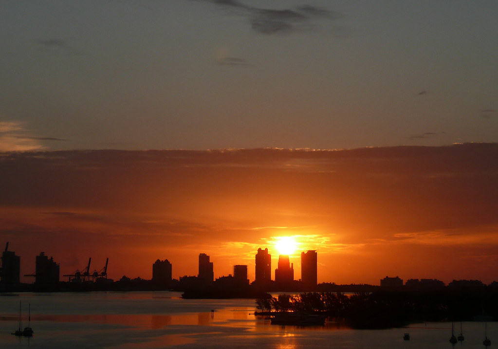 The Miami Beach and PortMiami skyline in silhouette at sunrise with port gantry cranes on the left