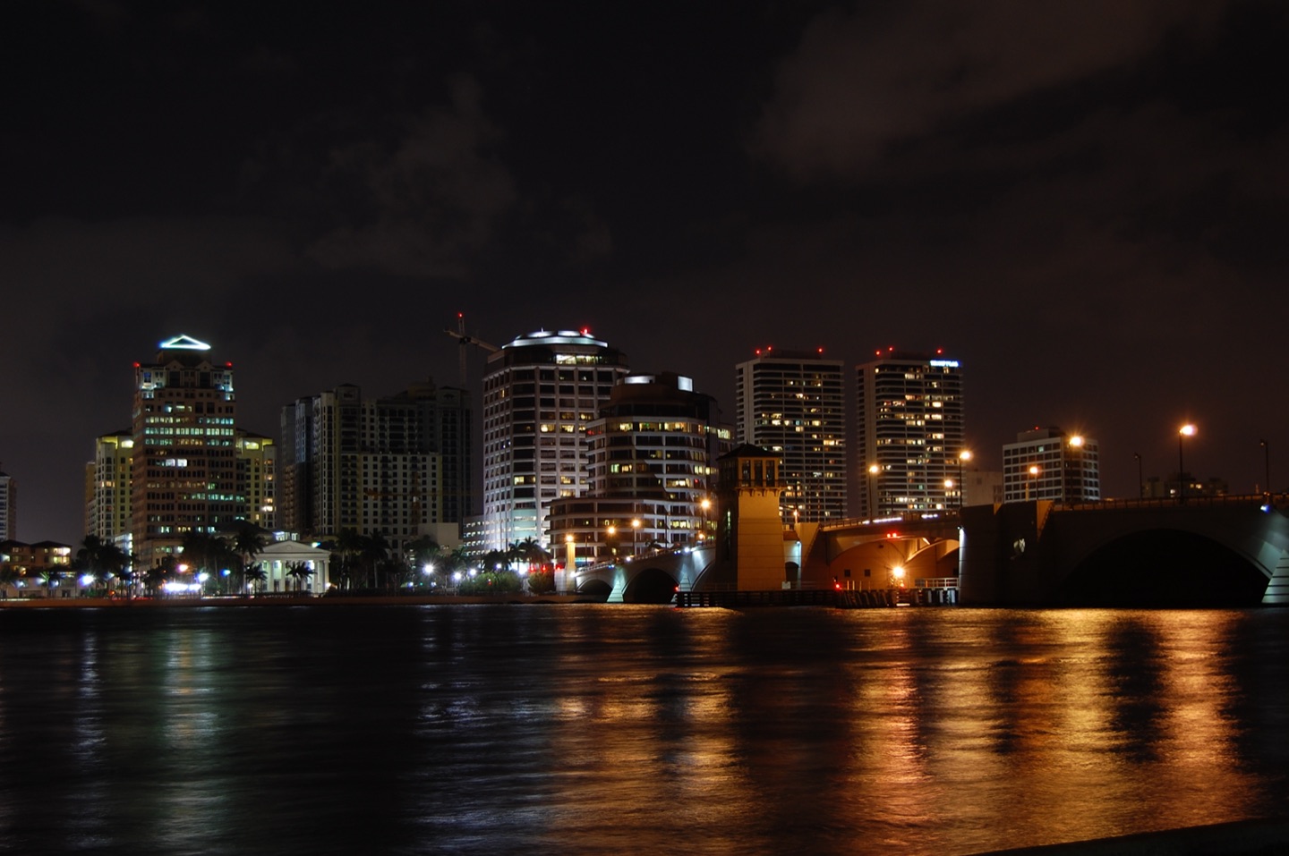 The West Palm Beach skyline lit at night across the Intracoastal with the bridge in the foreground